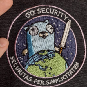 A machine-embroidered patch depicting a cartoon gopher holding a sword and towering over the planet earth. Around the border of the patch reads "Go Security" at the top and "Securitas Per Simplicitatem" at the bottom. The patch is four inches in diameter and inspired by the deranged National Reconnaissance Office NROL-39 mission patch.